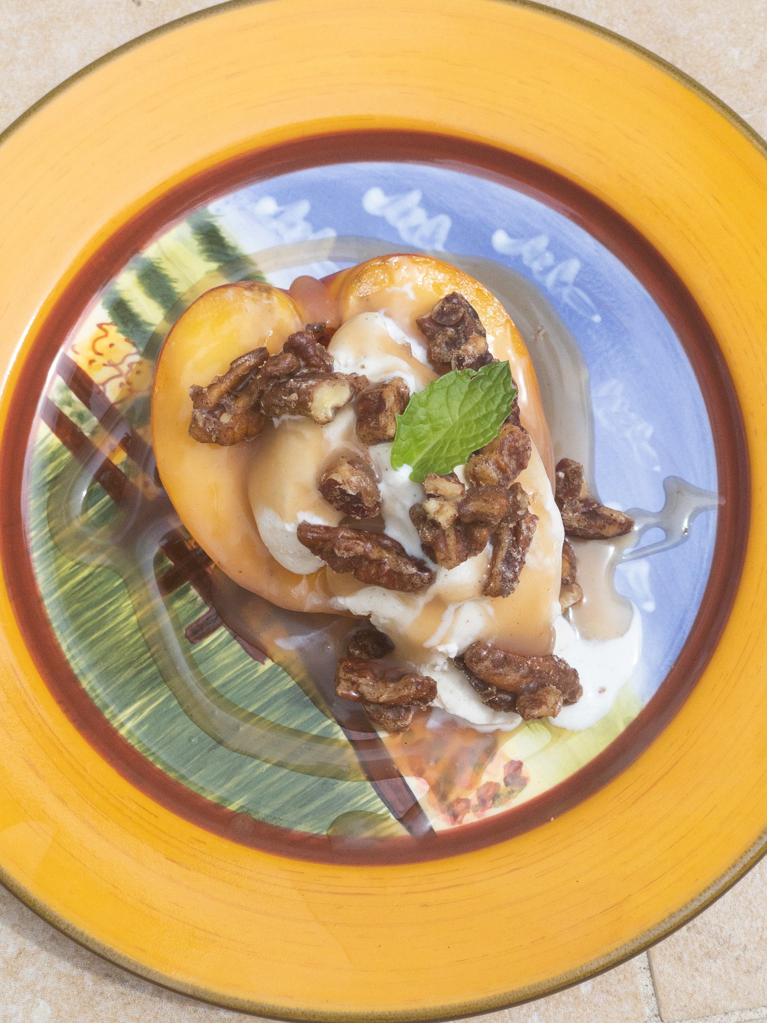 grilled peach topped with frozen yogurt, caramel and pecans